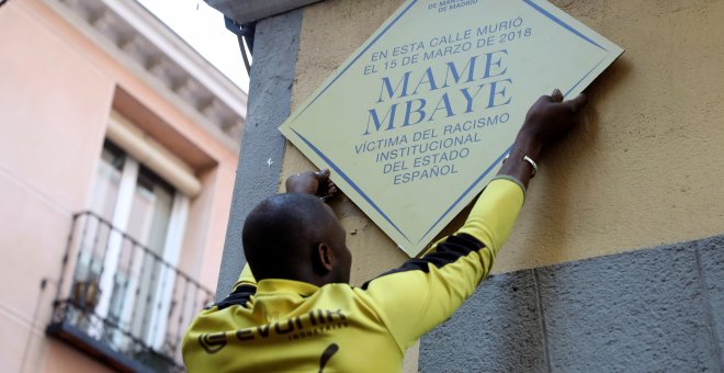 15/03/2019.- Un hombre coloca un placa durante la concentración convocada por el Sindicato de Manteros esta tarde en la plaza de Nelson Mandela, en Madrid, en recuerdo a Mame Mbaye, cuando se cumple un año de la muerte por un infarto de este vendedor sene