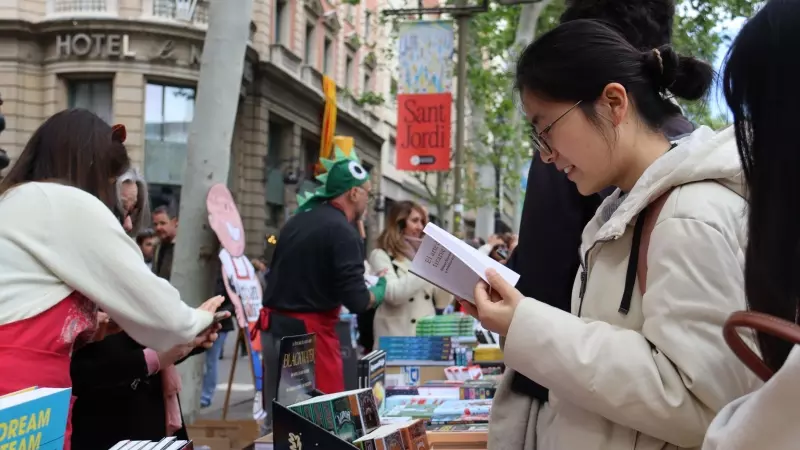 Una dona mira llibres en una parada de Les Rambles.