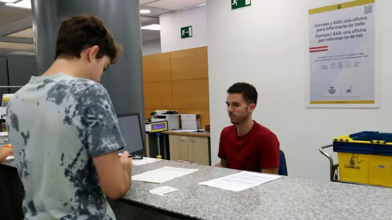 Un treballador de Correus explica el procediment per demanar el vot postal a un ciutadà