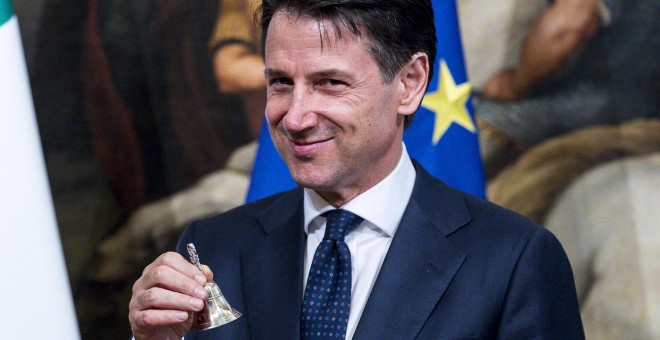 El nuevo primer ministro italiano, Giuseppe Conte, posa con una pequeña campana de plata entregada por el ahora exprimer ministro Paolo Gentiloni (no aparece) para abrir el primer Consejo de Ministros en el Palacio de Chigi, en Roma. EFE