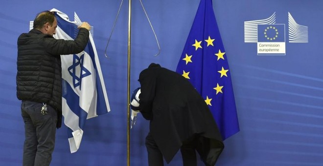 Empleados de la Comisión Europea retiran la bandera israelí en Bruselas, en una imagen de archivo. / AFP - JOHN THYS