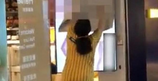 Una trabajadora de Ikea intenta tapar la pantalla del escaparate de una de las tiendas del gigante sueco en Hong Kong.