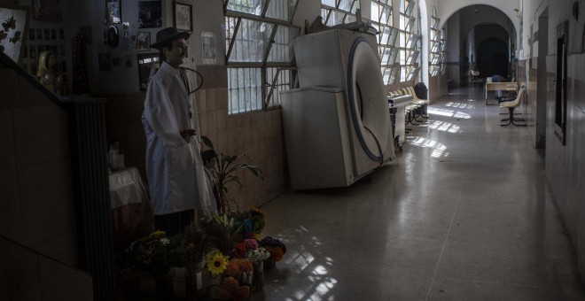 Un altar al médico Gregorio Hernández, junto a un tomógrafo averiado en un pasillo del Hospital Oncológico Luis Razetti de Caracas, Venezuela.- JAIRO VARGAS