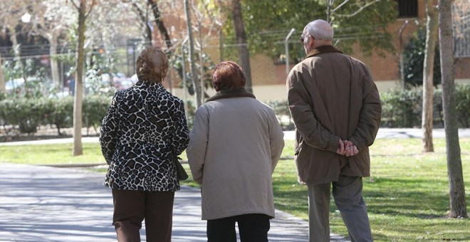 Pensionistas paseando por un parque.