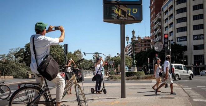 Varias personas fotografían un termómetro que marca 47 grados, este viernes en Valencia. EFE/Biel Aliño