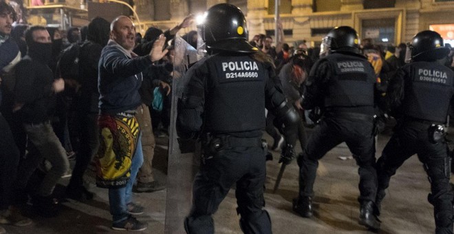 Un mediador pacifista trata de impedir que antidisturbios y encapuchados se enfrenten en Via Laietana, junto a Urquinaona, el pasado sábado, 18 de octubre, por la noche. GUILLEM SANS