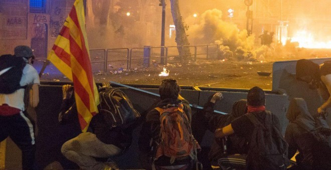 Jóvenes encapuchados se parapetan tras barricadas en el centro de la calle tras prender fuego a contenedores en el centro de Barcelona. GUILLEM SANS