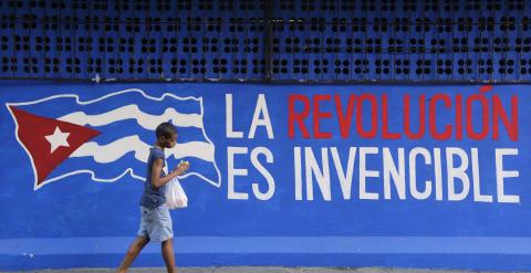 Un niño pasa junto a una pared en La Habana donde se puede leer: 'La Revolución es invencible'. - REUTERS