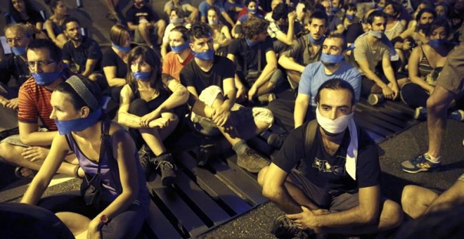 Manifestantes ante el Congreso de los Diputados, en Madrid, han acudido a la llamada de colectivos y organizaciones sociales, englobadas bajo el nombre 'gente sin mordaza', que han convocado a una sentada con la boca tapada en protesta por la entrada en v