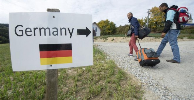 Cartel que indica a los refugiados sirios por dónde se va a Alemania, en la localidad austriaca de Julbach. / EFE