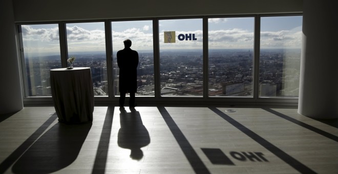 Un hombre mira a través de un ventanal de la sede en Madrid de la constructora OHL. REUTERS/Andrea Comas