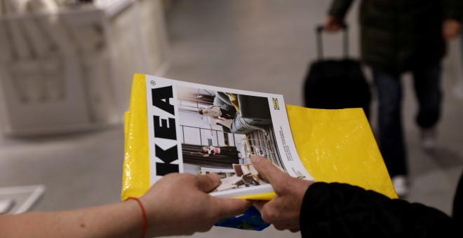 Un trabajador de Ikea entrega un catálogo a un cliente a la entrada de una de sus tiendas en Madrid. REUTERS/Susana Vera