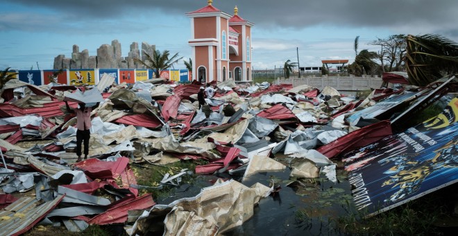 Personas recolectan láminas de metal de un supermercado dañado para reconstruir sus casas destruidas por el ciclón Idai en Beira, Mozambique | AFP/ Yasuyoshi Chiba