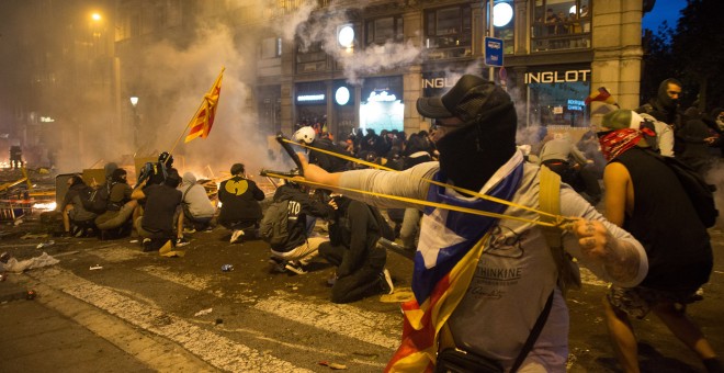 Jóvenes manifestantes se atrincheran en el centro de una calle de Barcelona y hacen frente a los antidisturbios. GUILLEM SANS