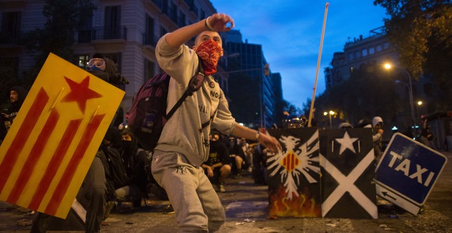Jóvenes con escudos de metal y los rostros cubiertos empiezan a retroceder ante el avance de los antidisturbios en el centro de Barcelona. GUILLEM SANS