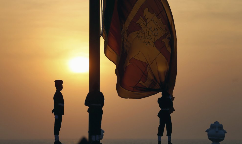 Un oficial de la fuerza aérea iza la bandera nacional de Sri Lanka al ponerse el sol en Galle Face Green en Colombo, Sri Lanka, 3 de febrero de 2016. Los habitantes celebrarán el 68º aniversario de día de la Independencia el 4 de febrero. REUTERS / Dinuka