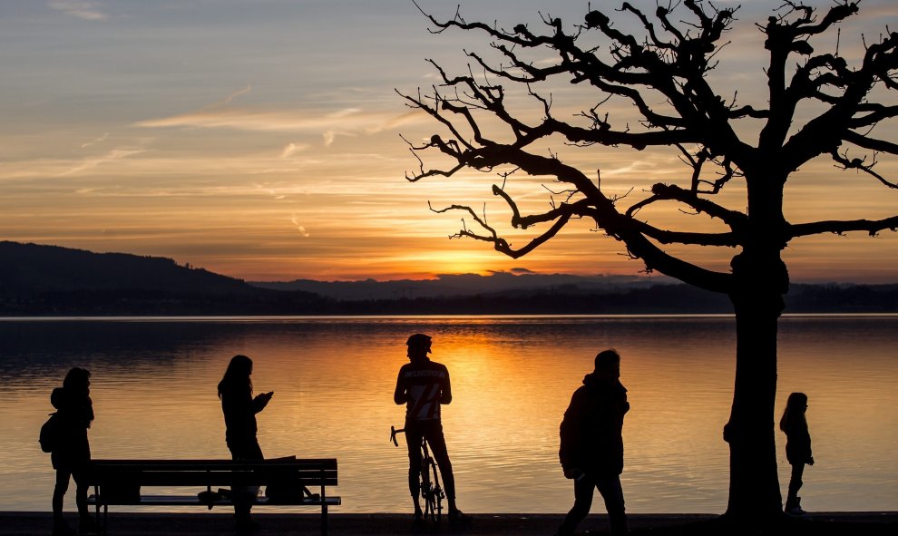 Un grupo de personas observa una puesta de sol en el lago Zug, Suiza. EFE/Alexandra Wey