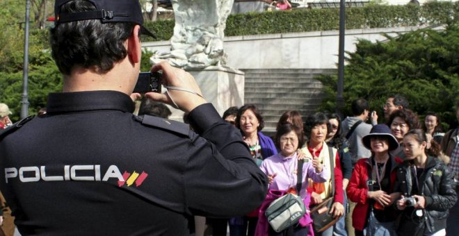 Un policía toma una foto a un grupo de turistas japoneses en Madrid.-EFE