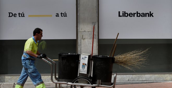 Un barrendero camina frente a una oficina de Liberbank en Oviedo. REUTERS/Eloy Alonso