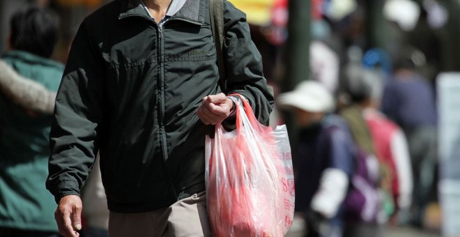 Un hombre carga una bolsa de plástico con la compra. AFP