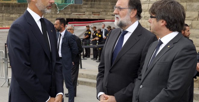 El rey de Felipe VI hablando con el presidente del Gobierno, Mariano Rajoy, y el presidente de la Generalitat de Cataluña, Carles Puigdemont, a su llegada a la basílica de la Sagrada Familia donde se celebró la Misa por la Paz en memoria de las víctimas d