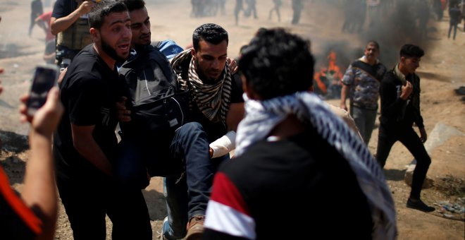 Varios palestinos trasladan a un herido en las protestas en Gaza contra la embajada de EEUU en Jerusalén. - REUTERS