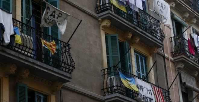 Pancartas que dicen "No a los apartamentos turísticos" cuelgan de un balcón para protestar contra los pisos para turistas en Barcelona. AFP