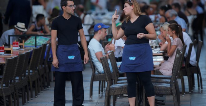 Una camarera conversa con un compañero de trabajo en una terraza de un restaurante en la localidad malagueña de Ronda. REUTERS/Jon Nazca