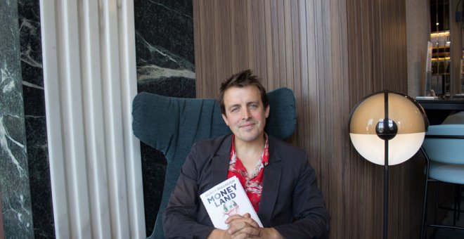 El periodista Oliver Bullough, autor de 'Moneyland', posa con su libro en un hotel de Madrid. (PRINCIPAL DE LOS LIBROS)