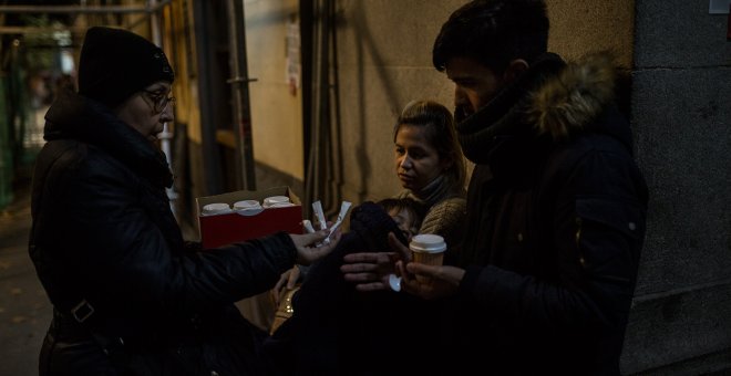 Una vecina voluntaria reparte café a una familia de solicitantes de asilo procedentes de Venezuela en las puertas del Samur Social de Madrid.- JAIRO VARGAS