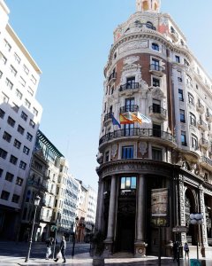 Detalle de la fachada de la sede social de Caixabank con la bandera de entidad y la de la Comunitat Valenciana ondeando al viento. EFE/Kai Försterling