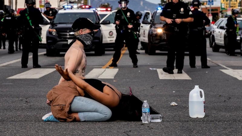Los manifestantes esperan su arresto por parte de la policía después del toque de queda durante las protestas por la muerte de George Floyd, en Van Nuys, Los Ángeles. EFE / ETIENNE LAURENT