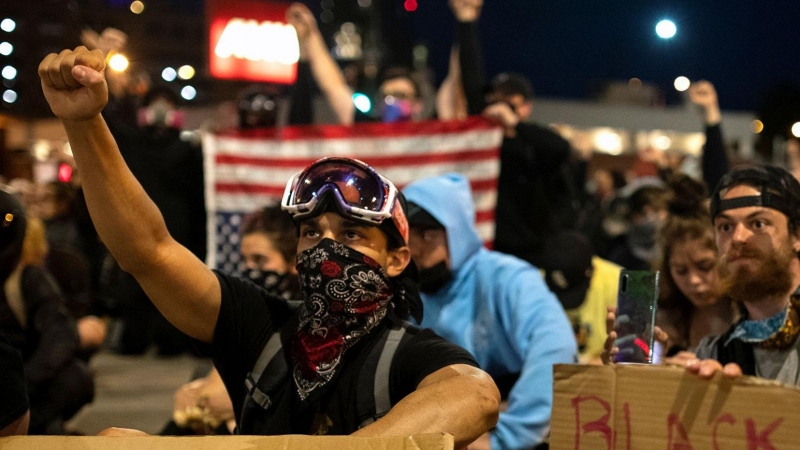 Los manifestantes con máscaras protectoras alzan los puños mientras se sientan en silencio durante nueve minutos en una protesta pacífica contra la muerte en la custodia policial de George Floyd, en Denver, Colorado. REUTERS / Alyson McClaran