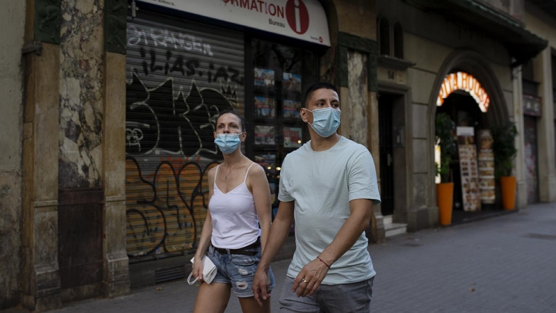Una parella passa per davant d'una oficina de turisme tancada, a Barcelona. LAIA ROS