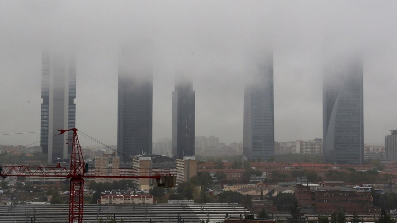 Vista de la lluvia y la niebla entre el complejo de las Cuatro Torres de Madrid a primera hora de la mañana.