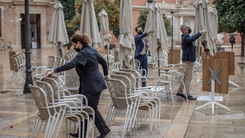 Unos trabajadores de un restaurante del centro de Valencia recogen la terraza. EFE/Biel Aliño