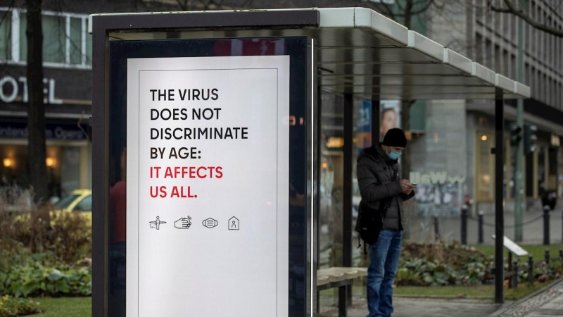 Un cartel advierte del riesgo de contagio de la covid-19 para cualquier edad, en una parada de autobús en Berlin.