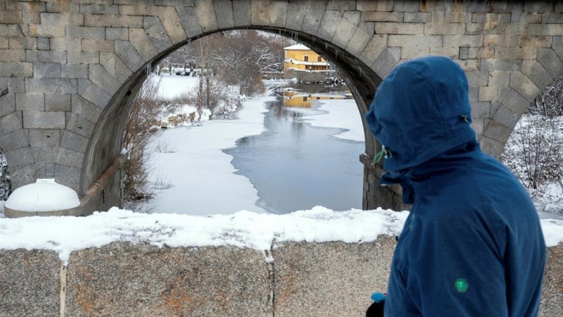 Un hombre observa el río Adaja, prácticamente congelado, a su paso por Ávila.
