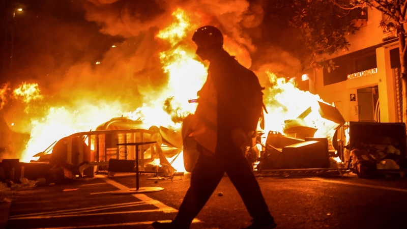 Una persona camina frente al fuego durante una protesta en apoyo del cantante de rap catalán Pablo Hasel