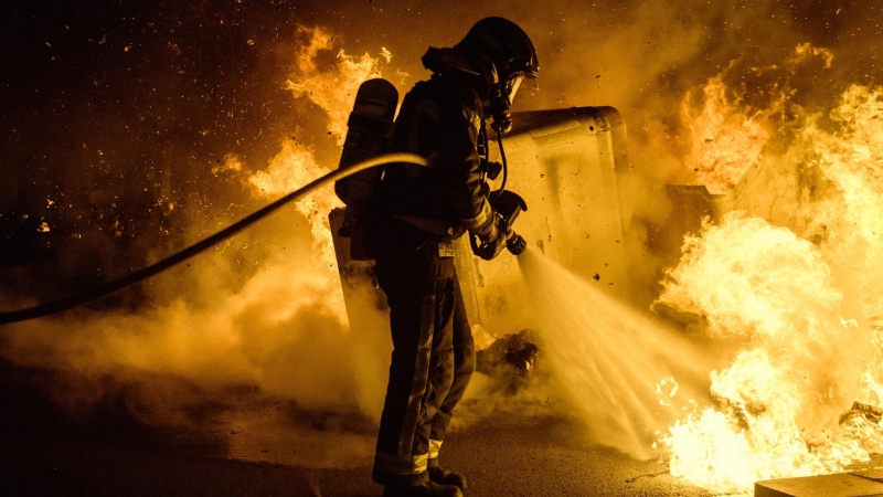 Un bombero apaga las llamas provocadas por los manifestantes durante las protestas de Barcelona en apoyo a Hasél.