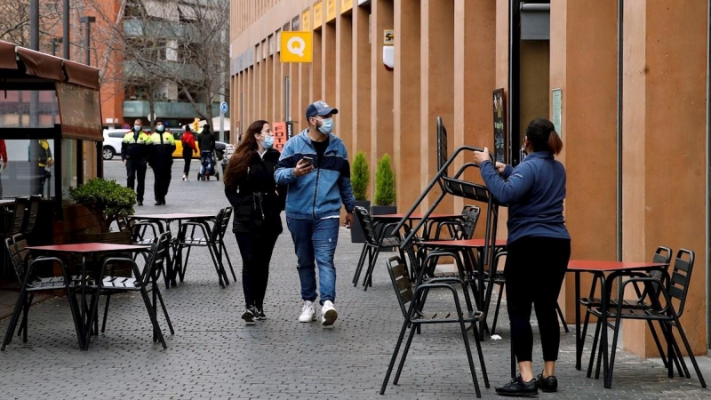 Una camarera prepara la terraza del restaurante donde trabaja para atender a sus clientes en L'Hospital de Llobregat.