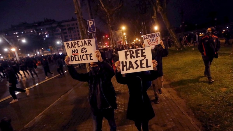 Manifestantes portan pancartas durante una nueva manifestación por la libertad de Pablo Hasel, después de seis días consecutivos de protestas que han finalizado con enfrentamientos con los Mossos d'Esquadra y daños a bienes públicos y privados, este lunes