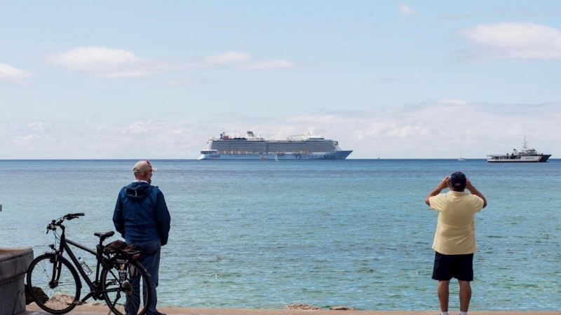 Unos hombres observan el crucero turístico 'Odissey of the Seas' fondeando este lunes en la bahía de Palma de Mallorca.