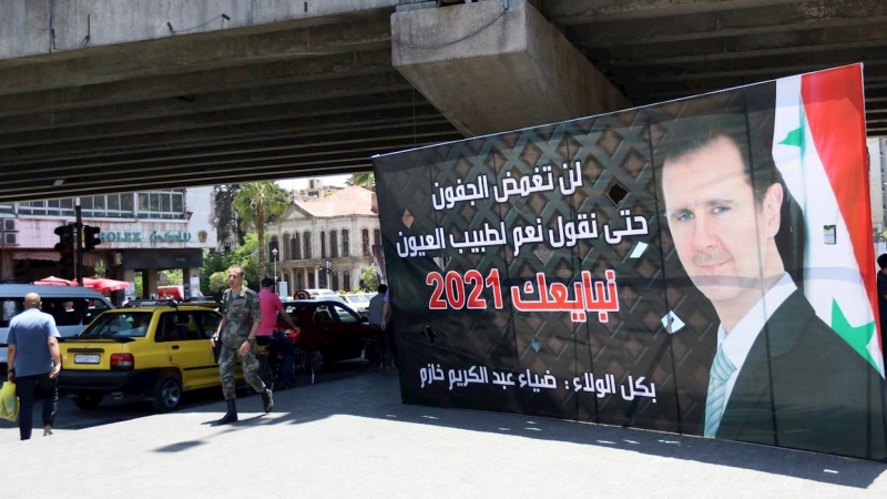 Varios peatones pasa junto a un cartel electoral que muestra al presidente sirio, Bachar Al Assad.