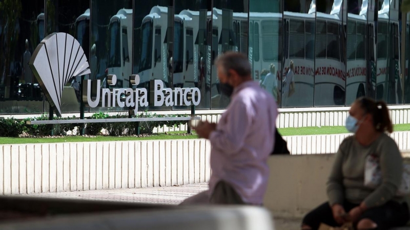 Dos personas en las inmediaciones de la sede de Unicaja Banco en Málaga. E.P./Álex Zea
