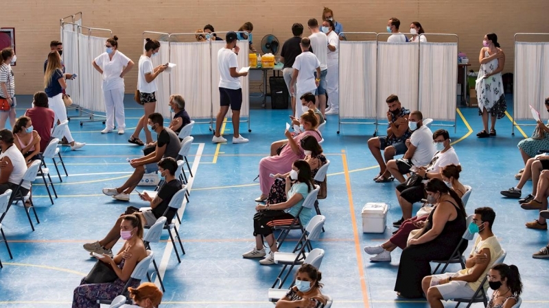 Multitud de jóvenes aguardan sentados tras recibir la vacuna contra el coronavirus en Espartinas, Sevilla.