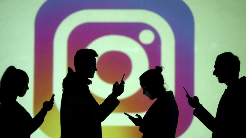 Varias siluetas de personas con su móvil, delante de un logo de la red social Instagram, propiedad de Facebook. REUTERS/Dado Ruvic/Illustration