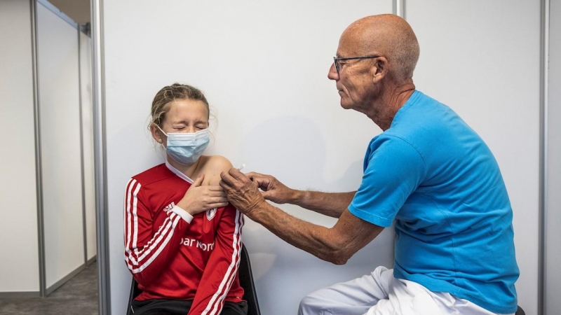 Un profesional sanitario pone una dosis de la vacuna contra la covid a una menor en Dinamarca.
