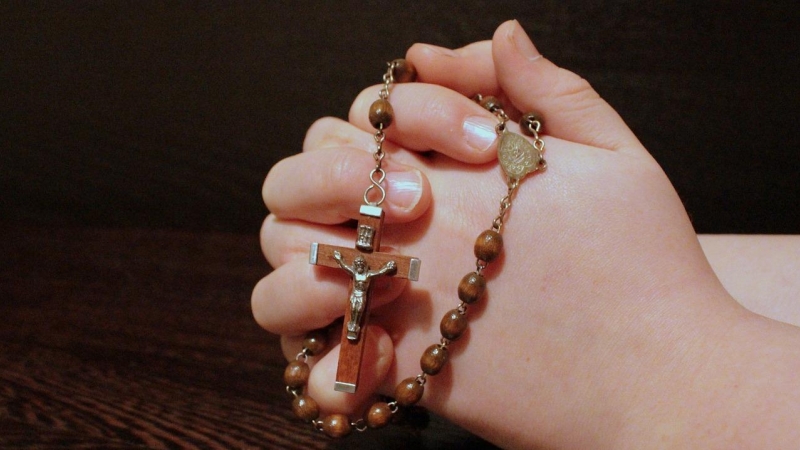 Foto de archivo. Un niño rezando con un rosario.
