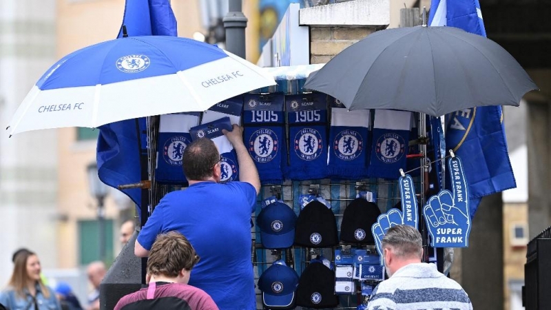 Un vendedor instala su puesto de mercadería fuera de Stamford Bridge antes del partido de fútbol de la Premier League inglesa entre Chelsea y Wolverhampton Wanderers, en Londres el 7 de mayo de 2022. Chelsea confirmó el sábado que un consorcio liderado po